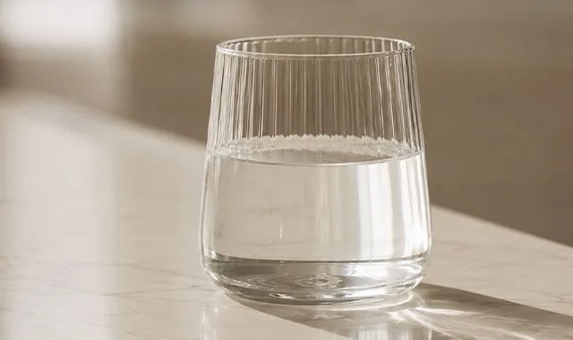 A ribbed glass of clear Kangen Water® on a sunlit counter